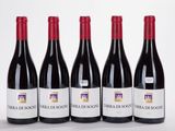 four bottles of red wine are lined up on a white surface