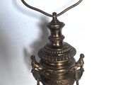 une vieille lampe en laiton surmontée d'une clochette, posée sur une table