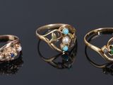 three gold rings with green and white stones on a black surface