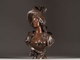 bronze bust of a woman with a hat on her head