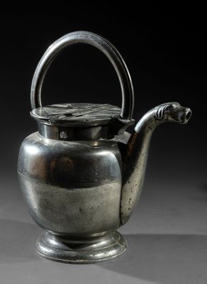 an old silver tea pot with a handle sitting on a table