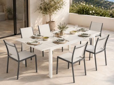a white table and chairs on a patio with a view of the ocean