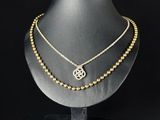 a gold necklace with a medallion on a black mannequin