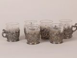 four glass cups with handles are lined up on a white surface