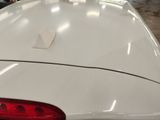 the rear end of a white car with a sticker on it ' s hood