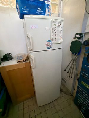 un réfrigérateur blanc dans une petite cuisine, avec une boîte bleue posée dessus