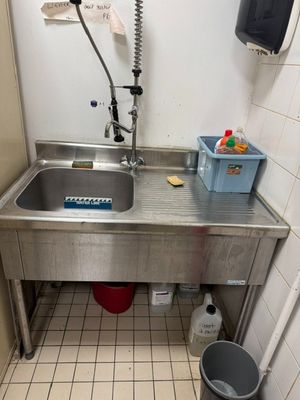 un lavabo dans une salle de bains, avec une poubelle à côté
