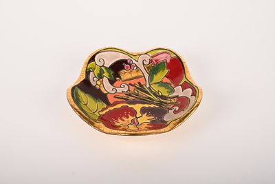 assiette jaune, rouge et blanche représentant une femme dans un bateau tenant un bouquet de fleurs