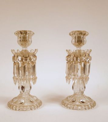 une paire de bougeoirs en verre transparent posés sur une surface blanche