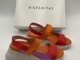 une paire de sandales orange et violettes posées devant une boîte