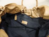 someone is holding a tan purse with a black bag inside of it