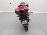 a red motorcycle parked in a room with a white wall