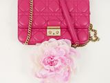 pink quilted purse with a flower on a white background