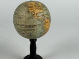 a small globe on a black stand on a white surface