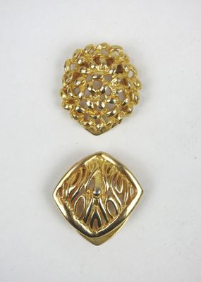 un gros plan sur deux broches dorées posées sur une surface blanche