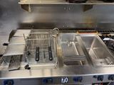 stainless steel counter top with two deep fryers and a frying pan