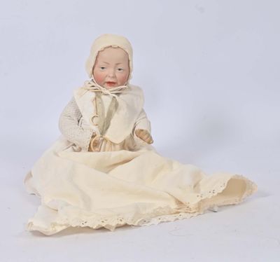a small doll sitting on a blanket on a white surface