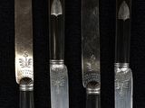 four knives are lined up in a row on a black surface