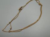 un gros plan d'un collier en or avec une chaîne posé sur une table