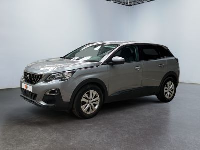La voiture grise est garée dans une grande pièce aux murs blancs.