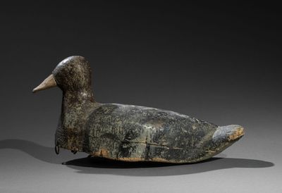 un vieux canard en bois posé sur une surface grise