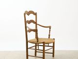 an image of a wooden chair with a woven seat on a white floor