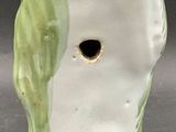 a white vase with a green bird on it