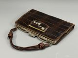 portefeuille en cuir d'alligator marron avec un fermoir métallique sur fond blanc