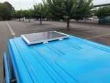 a solar panel on top of a blue truck in a parking lot
