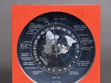 an orange clock sitting on top of a table next to a white clock