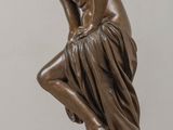 statue of a woman sitting on a rock with her hands on her knees
