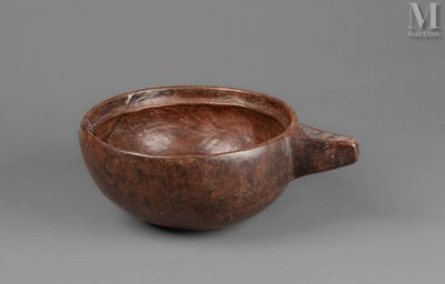an old wooden bowl with a handle on a gray surface