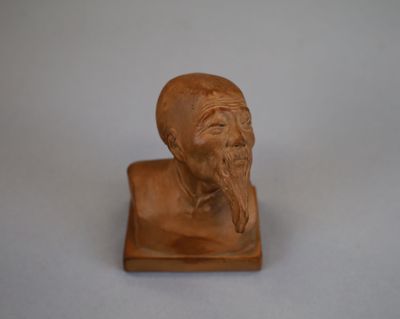 une petite statue représentant un homme barbu posée sur une surface blanche