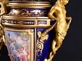 a blue and gold vase with two cherensils on it