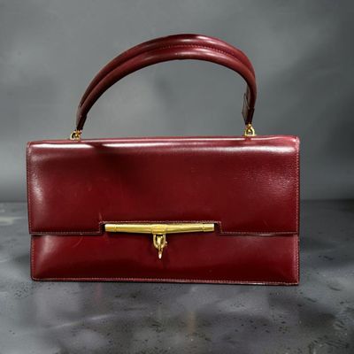 un sac à main en cuir rouge avec une poignée dorée, posé sur une table