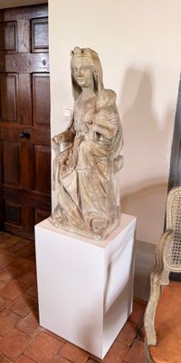 une statue représentant une femme assise sur un socle à côté d'une chaise