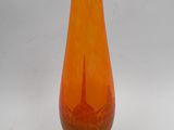 un vase en verre orange posé sur un socle en bois