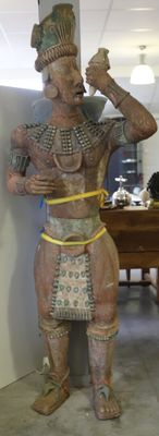 une statue représentant un homme debout à côté d'une table