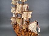 wooden model of a tall sailing ship with sails and a flag