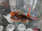 une vitrine en verre sur laquelle sont posés un poisson, des tasses et des soucoupes