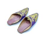 une paire de pantoufles violettes et dorées posées sur une surface blanche