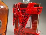 a bottle of liquor next to a bottle of liquor wrapped in red ribbon