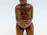 a small wooden figure of a man sitting on a stool