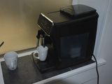 a black coffee machine sitting on top of a counter next to a cup