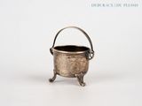 une vieille théière en argent posée sur une table blanche