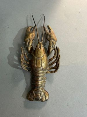un homard en métal accroché au mur, à côté d'une lampe