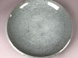 a gray plate with a white rim sitting on a pink surface