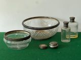 a green table with a glass bowl and a bottle of perfume on it