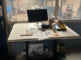 un bureau sur lequel est posé un ordinateur portable, devant une fenêtre