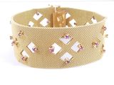 a close up of a gold bracelet with pink stones on a white background